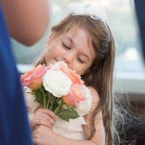 Little girl smelling flowers at christening function